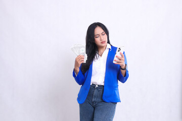 beautiful adult office female wearing blue formal suit standing angry to gadget carrying dollar money and smartphone isolated white background. for transaction, finance, business content