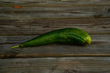 A young luffa squash laying on a picnic table.