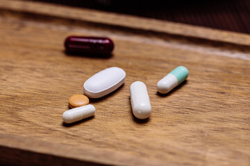 Close-up of various pills and capsules on wooden tray