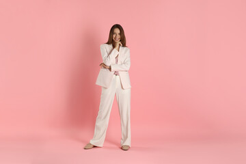 Beautiful woman in stylish white suit on pink background