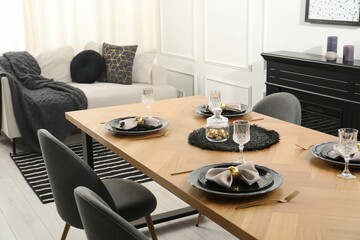 Stylish table setting with black dishware in dining room