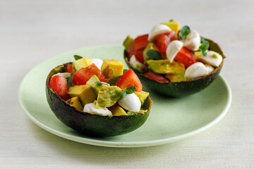 Avocado boats stuffed with mozzarella cheese, arugula and cherry tomatoes. Salad. Healthy food and dieting concept