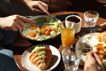 Couple having tasty breakfast at wooden table in cafe, closeup