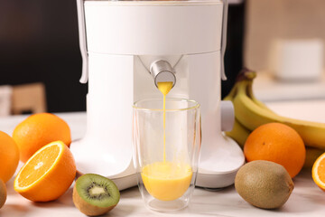 Modern juicer, fresh fruits and glass on white marble table in kitchen, closeup