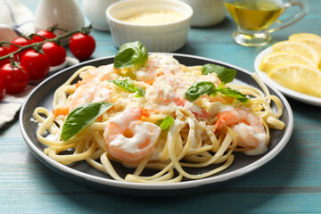 Tasty pasta with shrimps on light blue wooden table, closeup