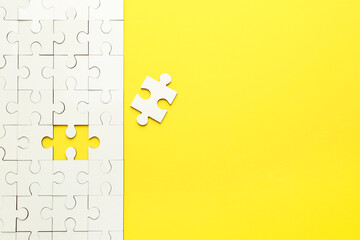 White puzzle pieces on yellow background, top view. Space for text