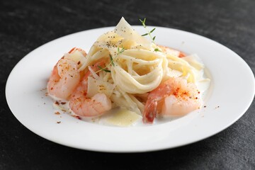 Delicious pasta with shrimps and cheese on black table, closeup