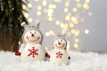 Funny snowman figure on artificial snow against blurred lights