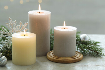 Burning candles, baubles and fir tree branches on white textured table, closeup