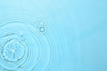 Rippled surface of clear water on light blue background, top view