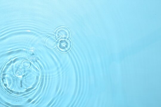 Rippled surface of clear water on light blue background, top view