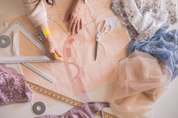 A woman seamstress designs and draws a pattern for underwear on graph paper. 
