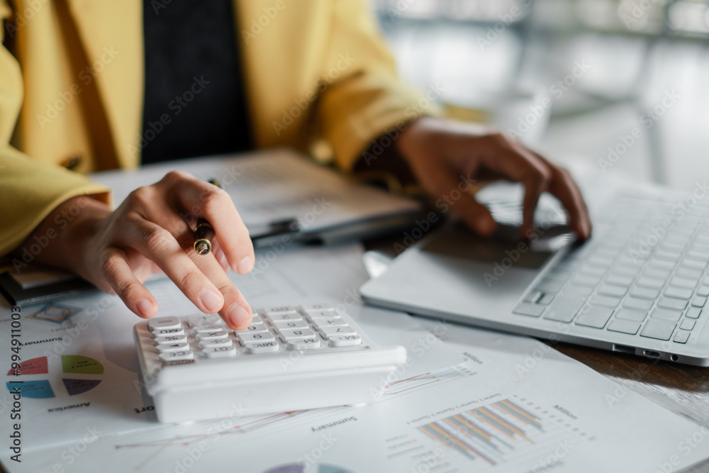 Poster close-up of a businesswoman's hands using a calculator and laptop for financial analysis with charts