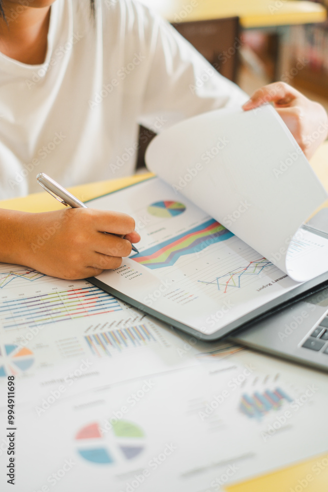 Poster close-up of a business professional analyzing financial charts and graphs on paper and laptop in an 