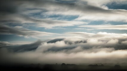 Obraz premium Misty morning sky with low drifting clouds