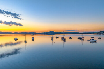 Autumn sunrise over the bay with boats and reflections