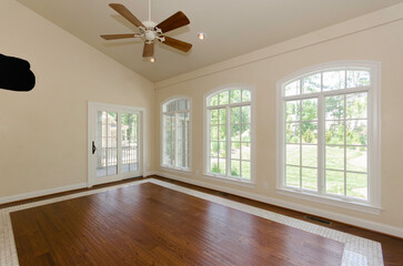 Room With Wooden Floor, Ceiling Fan, And Large Windows