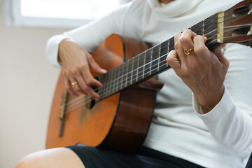 Closeup hands of young asian woman sitting and playing guitar, skill and practice, guitarist and hobby with enjoyment and relax, entertainment and lifestyle.