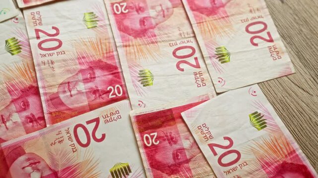 Israeli shekel banknotes scattered on a wooden surface