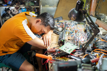 technician falls asleep due to tiredness working on repairing electronics at the workbench