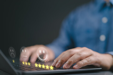 Customer satisfaction survey concept, Businessman using computer laptop select smiley face icon with yellow five stars to evaluate product and service.