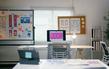 Modern, bright office where ux/ui designers collaborate on a new mobile app, with wireframes and...