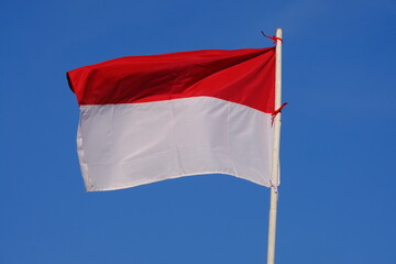 the red and white flag flutters in the wind. the blue sky. the flag of the republic of Indonesia.