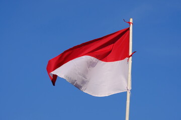 the red and white flag flutters in the wind. the blue sky. the flag of the republic of Indonesia.