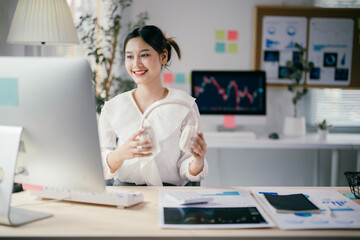 Young businesswoman is putting on her headphones, getting ready to work on her computer at her bright and modern office