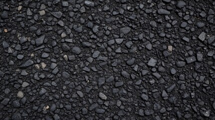 Close-up view of textured dark asphalt with small stones and gravel, suitable for backgrounds, roads, and construction projects.