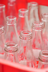 Empty glass bottles arranged in a vibrant red basket for storage and organization