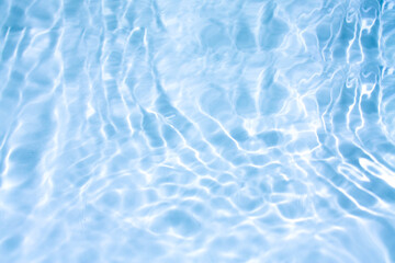 Obraz premium Blue water with ripples on the surface. Defocus blurred transparent blue colored clear calm water surface texture with splashes and bubbles. Water waves with shining pattern texture background.