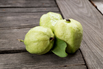 Group of guava fruits isolated on wooden floor with green leaf close up.