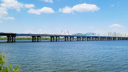 Obraz premium panorama view of the river, Yeouido Hangang River Park, in Seoul, Korea, with a broad bridge, and a cityscape in the backdrop 