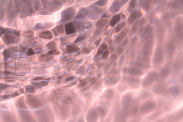 Pink water bubbles on the surface ripples. Defocus blurred transparent pink colored clear calm water surface texture with splash and bubbles. Water waves with shining pattern texture background