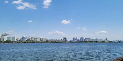 Fototapeta premium panorama view of the river, Yeouido Hangang River Park, in Seoul, Korea, with a broad bridge, and a cityscape in the backdrop 