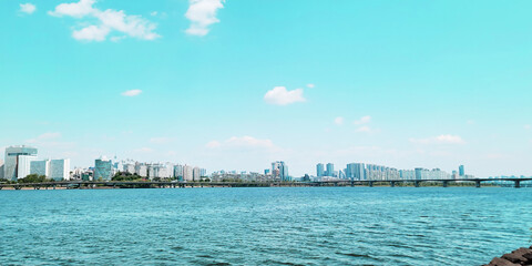 Naklejka premium panorama view of the river, Yeouido Hangang River Park, in Seoul, Korea, with a broad bridge, and a cityscape in the backdrop 