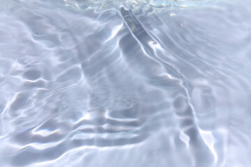 White water with ripples on the surface. Defocus blurred transparent white colored clear calm water surface texture with splashes and bubbles. Water waves with shining pattern texture background.