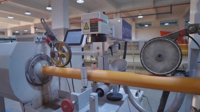 Close-up view of machinery used in the production of yellow PVC pipes in a modern industrial facility, showcasing advanced manufacturing technology.
