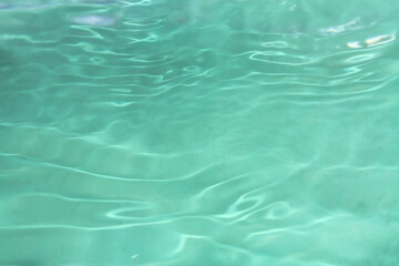 Defocus blurred transparent green colored clear calm water surface texture with splashes and bubbles. Trendy abstract nature background. Water waves in sunlight with copy space. Green water shine