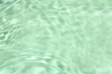 Defocus blurred transparent green colored clear calm water surface texture with splashes and bubbles. Trendy abstract nature background. Water waves in sunlight with copy space. Green water shine