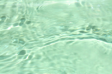 Defocus blurred transparent green colored clear calm water surface texture with splashes and bubbles. Trendy abstract nature background. Water waves in sunlight with copy space. Green water shine