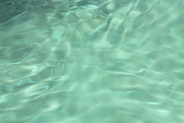 Defocus blurred transparent green colored clear calm water surface texture with splashes and bubbles. Trendy abstract nature background. Water waves in sunlight with copy space. Green water shine