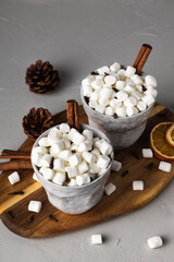 Mugs of hot drink with marshmallows on wooden tray. Grey Cups of hot Chocolate drink with cinnamon on concrete background. Autumn or Winter time and Holiday concept
