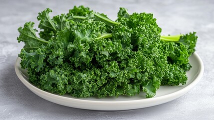 Vibrant green kale leaves are elegantly arranged on a white plate with a soft gray background.