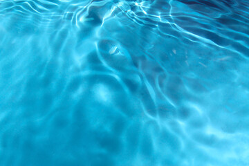 Bluewater waves on the surface ripples blurred. Defocus blurred transparent blue colored clear calm water surface texture with splash and bubbles. Water waves with shining pattern texture background 