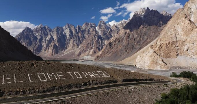 Welcome to Passu Sign in Hunza Valley with Passu Cones Mountains in Background