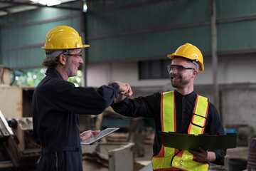 Two male engineer join hands together in industry factory. Finished, completed work concept
