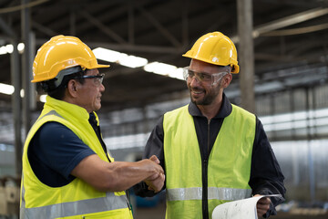 Two male engineer join hands together in industry factory. Finished, completed work concept