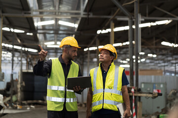 Two male engineer worker discuss and working together in industry factory. Male engineer repairing or maintenance CNC machine in factory